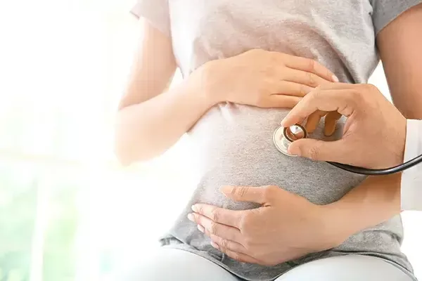 Doctor listening to a baby's heartbeat on the pregnant lady's belly